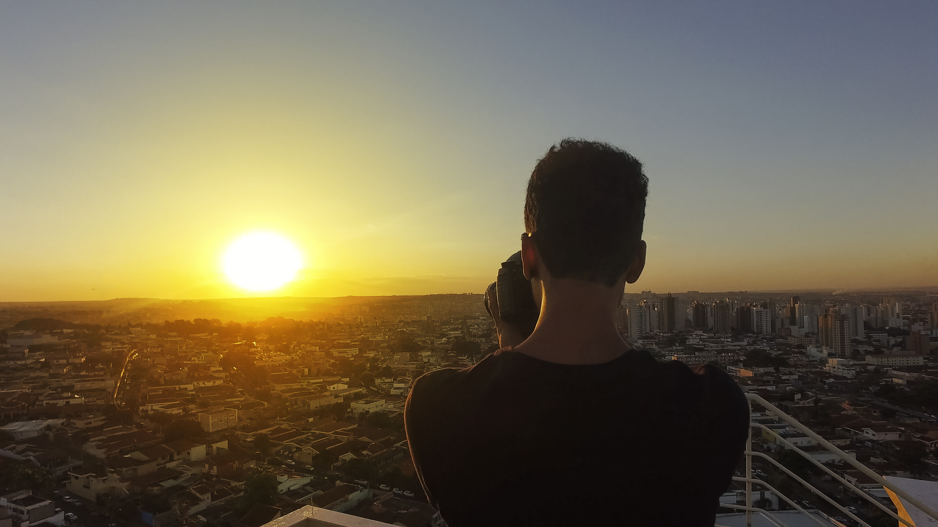 Fotógrafo no topo do prédio ao pôr do sol