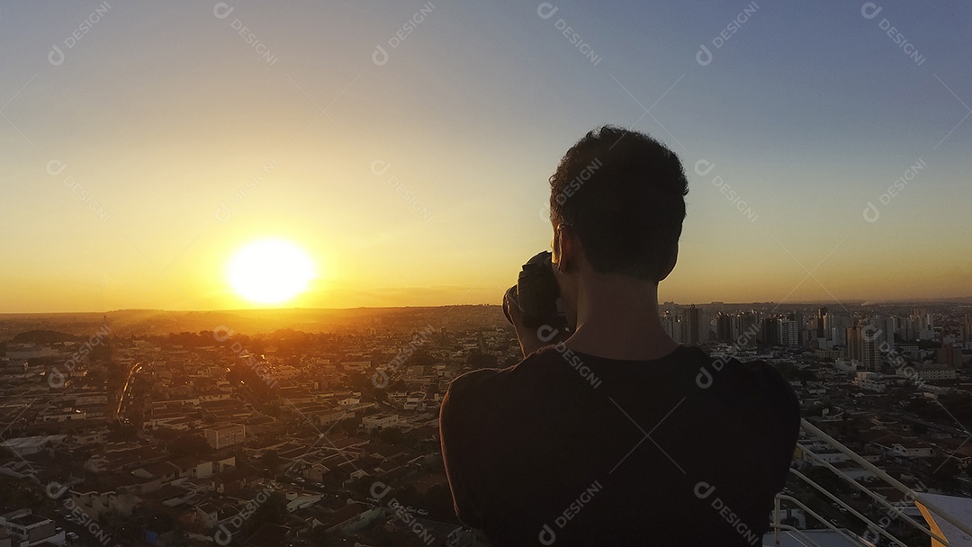 Fotógrafo no topo do prédio ao pôr do sol
