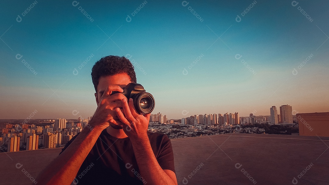 Fotógrafo no topo do prédio ao pôr do sol
