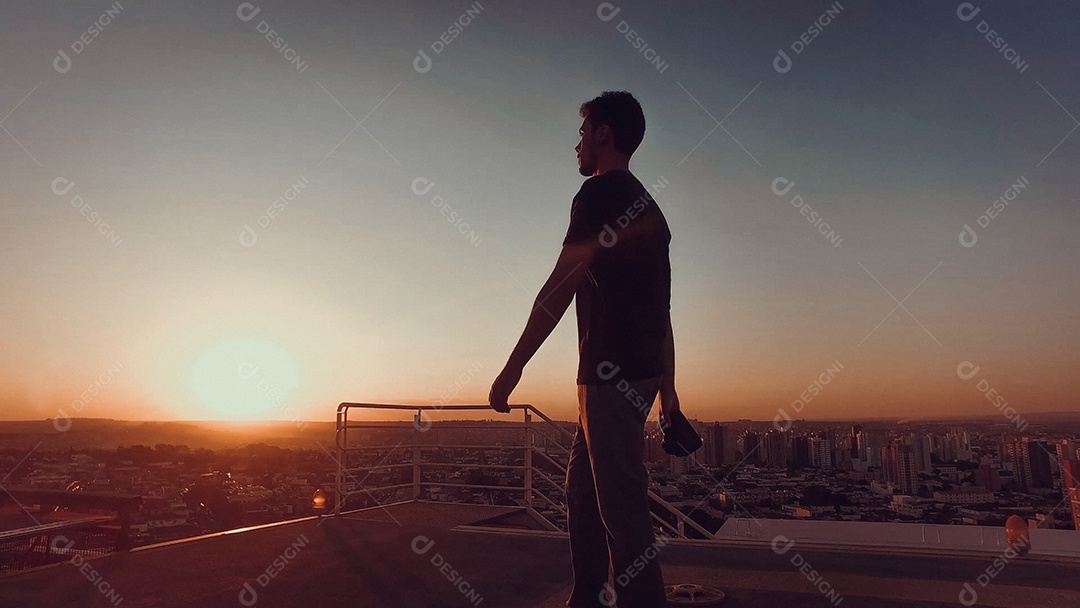 Fotógrafo no topo do prédio ao pôr do sol