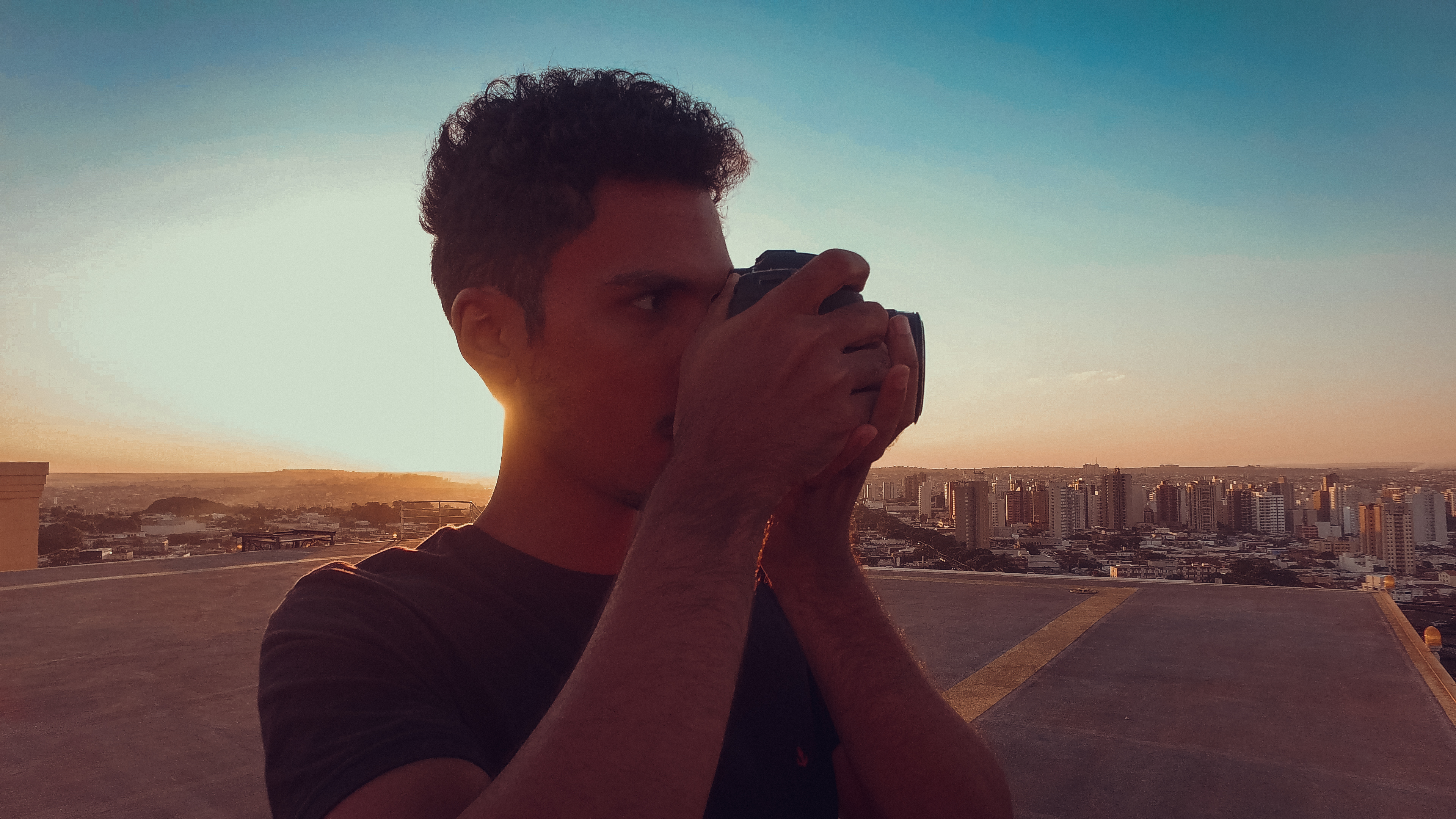 Fotógrafo no topo do prédio ao pôr do sol