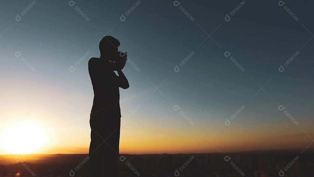 Silhueta de fotógrafo de homem ao pôr do sol