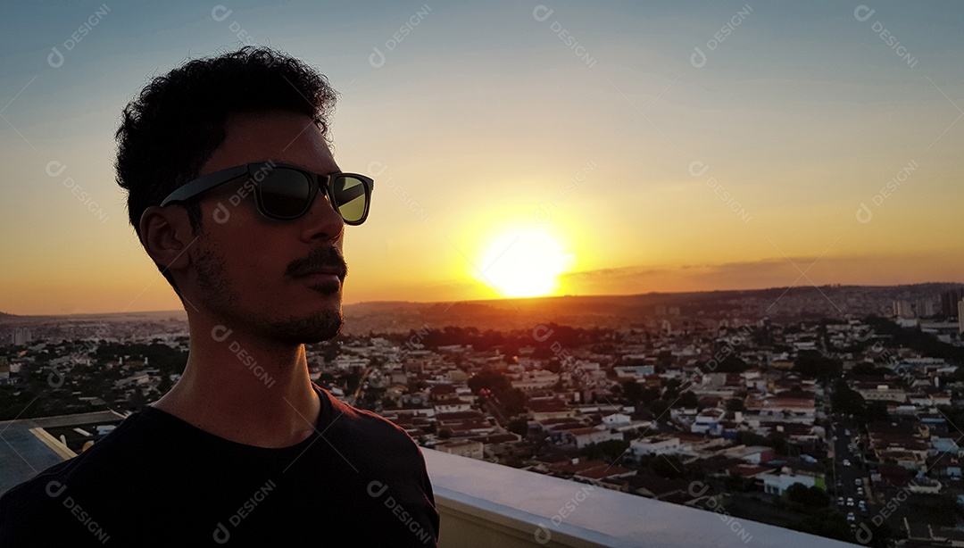 Silhueta de um homem no topo de um edifício por do sol na cidade