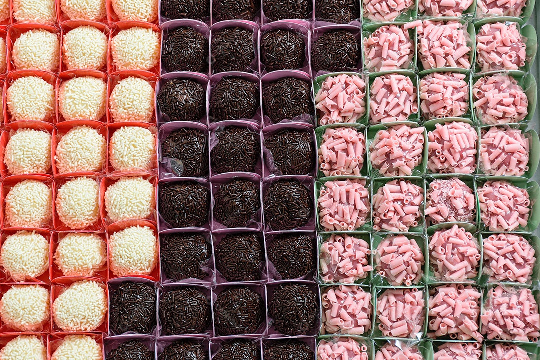Vários tipos de brigadeiros organizados em fileiras. Brigadeiros de chocolate