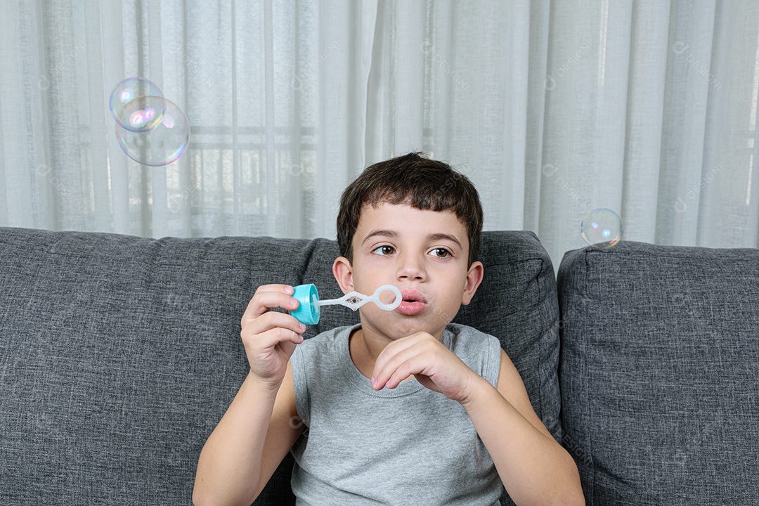 Criança de 7 anos, surpresa, observando uma bolha de sabão.