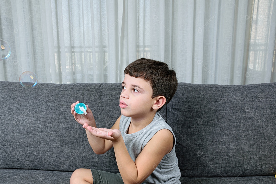 Criança de 7 anos, surpresa, observando uma bolha de sabão.