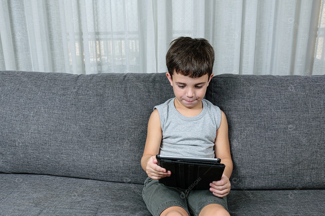 Criança de 7 anos, apontando para o tablet se divertindo