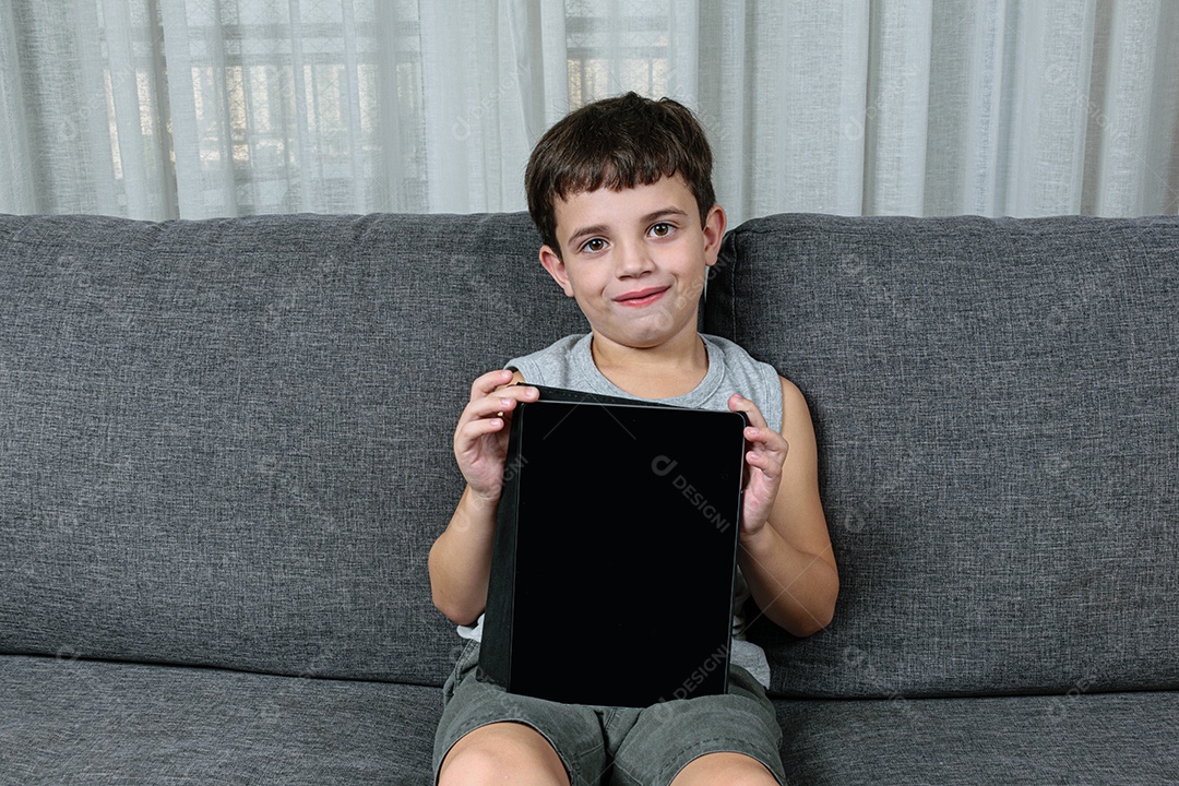 Criança de 7 anos, apontando para o tablet se divertindo