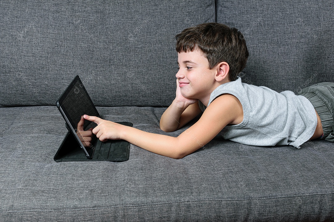 Criança de 7 anos, apontando para o tablet se divertindo
