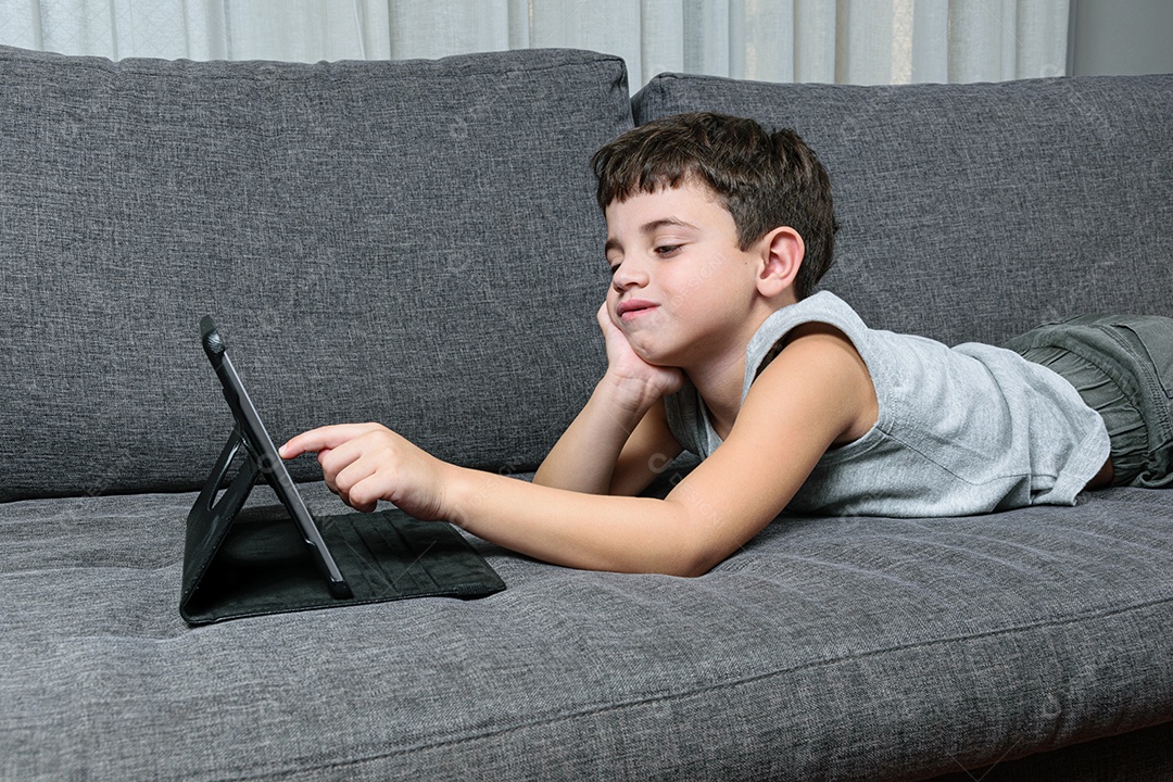 Criança de 7 anos, apontando para o tablet se divertindo