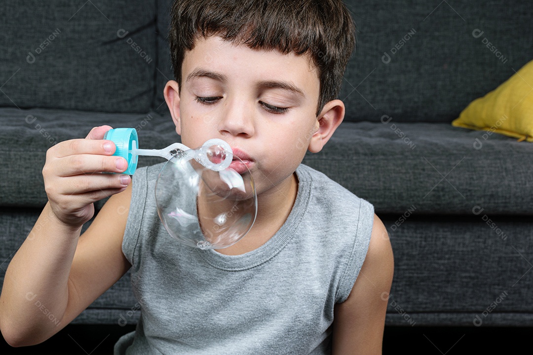 Criança de 7 anos, surpresa, observando uma bolha de sabão.