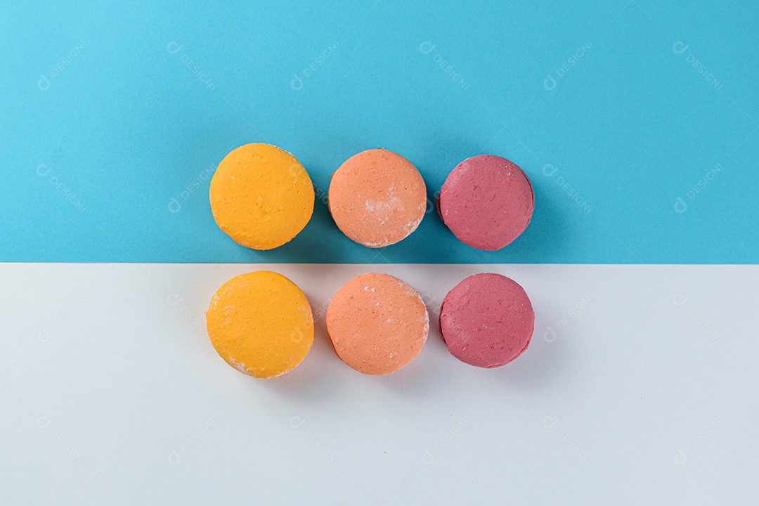 Porção de biscoitos coloridos sobre um fundo branco e azul.