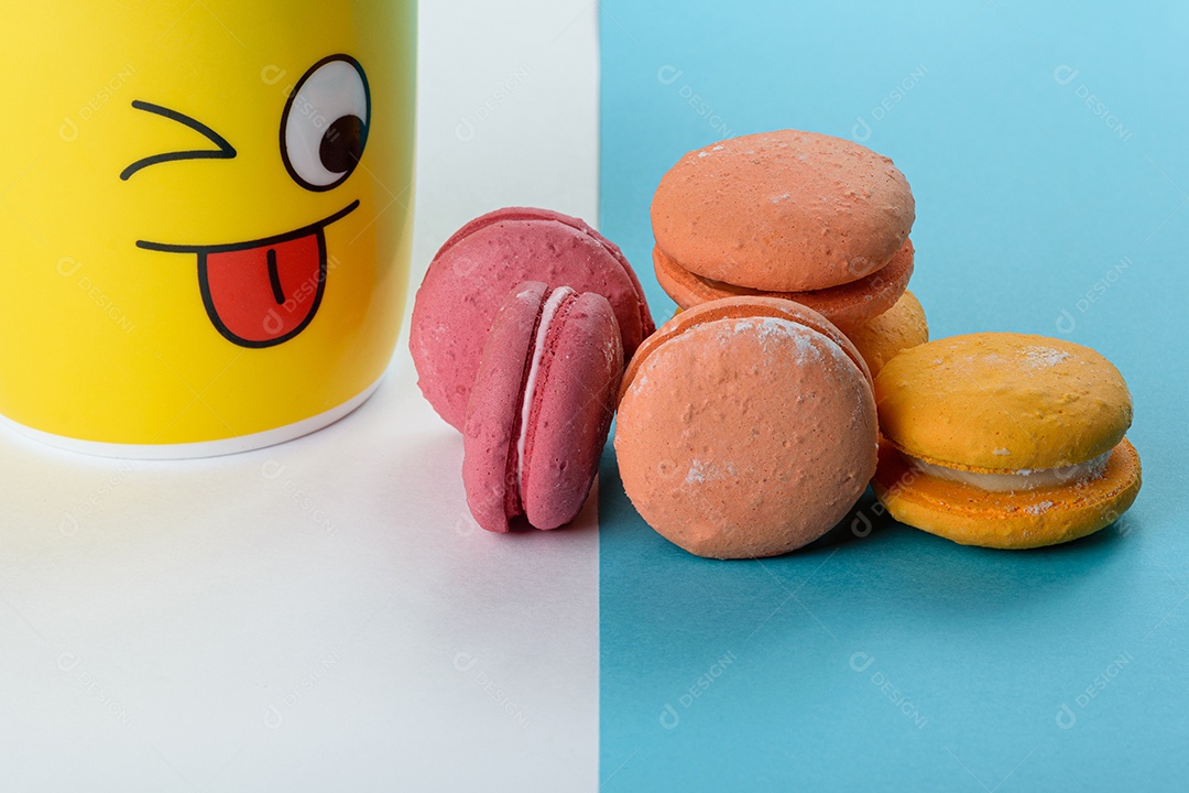 Parcela de biscoitos coloridos sendo observados por uma caneca amarela.