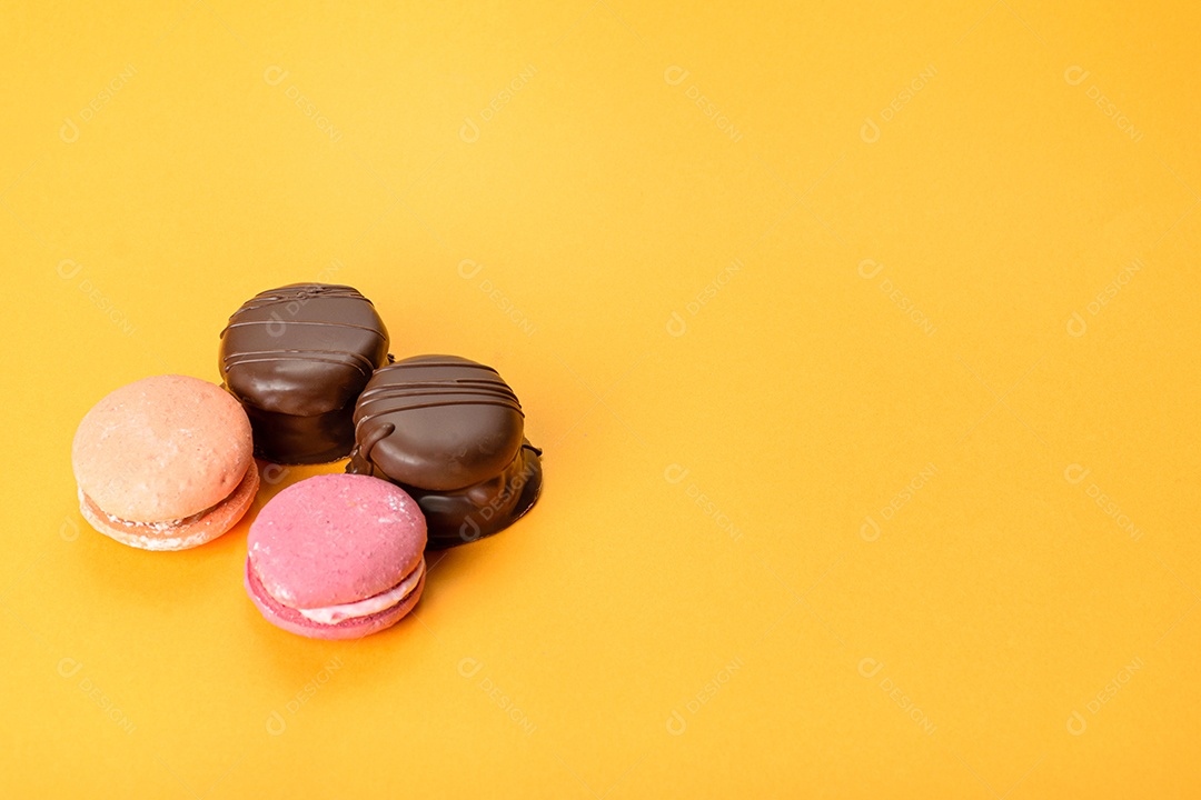 Macarons e bolos de mel brasileiros em um fundo laranja.