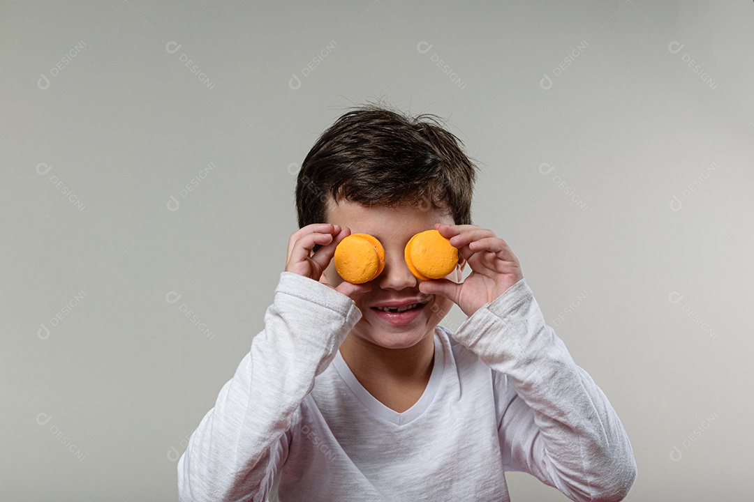 Criança de 6 anos segurando um biscoito rosa e com um grande sorriso no rosto.