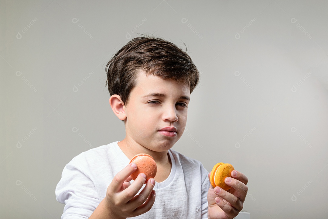 Criança de 6 anos segurando um biscoito rosa e com um grande sorriso no rosto.