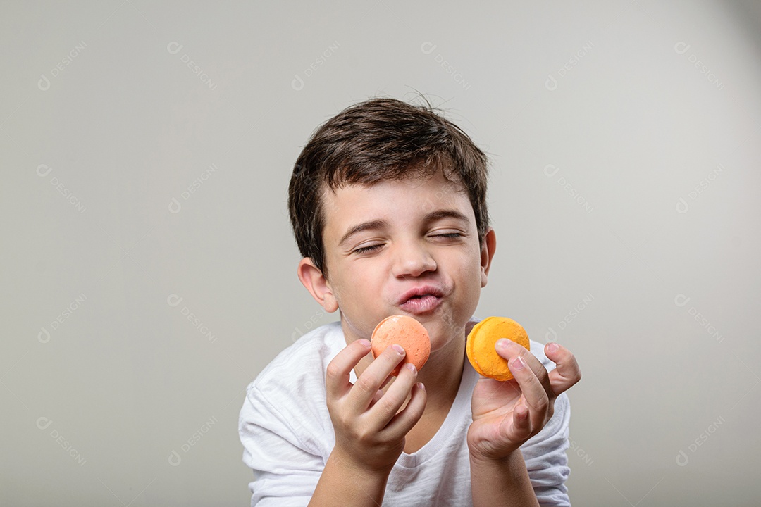 Criança de 6 anos segurando um biscoito rosa e com um grande sorriso no rosto.