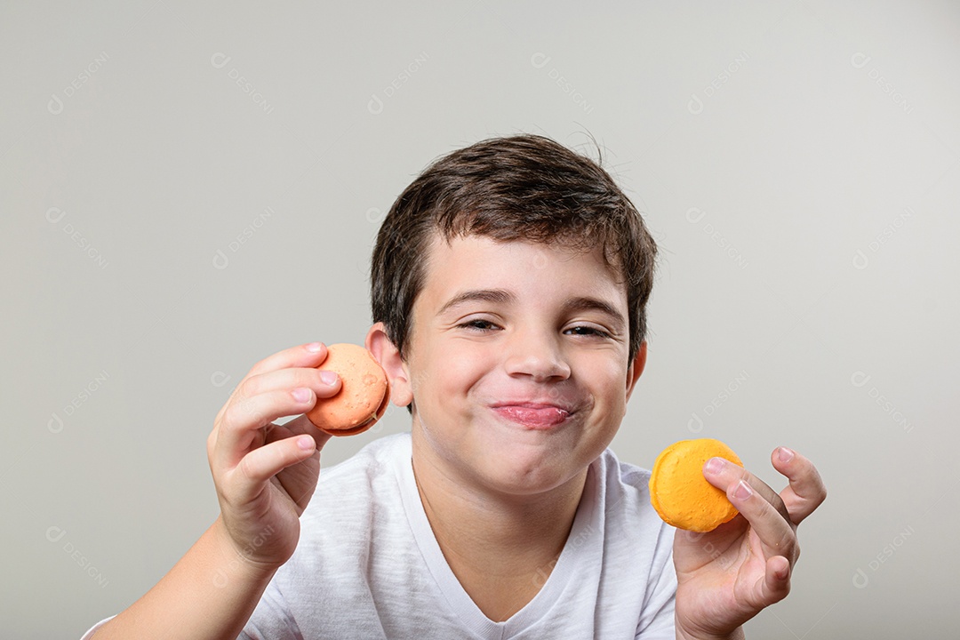 Criança de 6 anos segurando um biscoito rosa e com um grande sorriso no rosto.