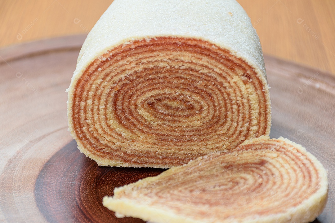 Fatias de bolo de rolo no centro de uma tábua de madeira.