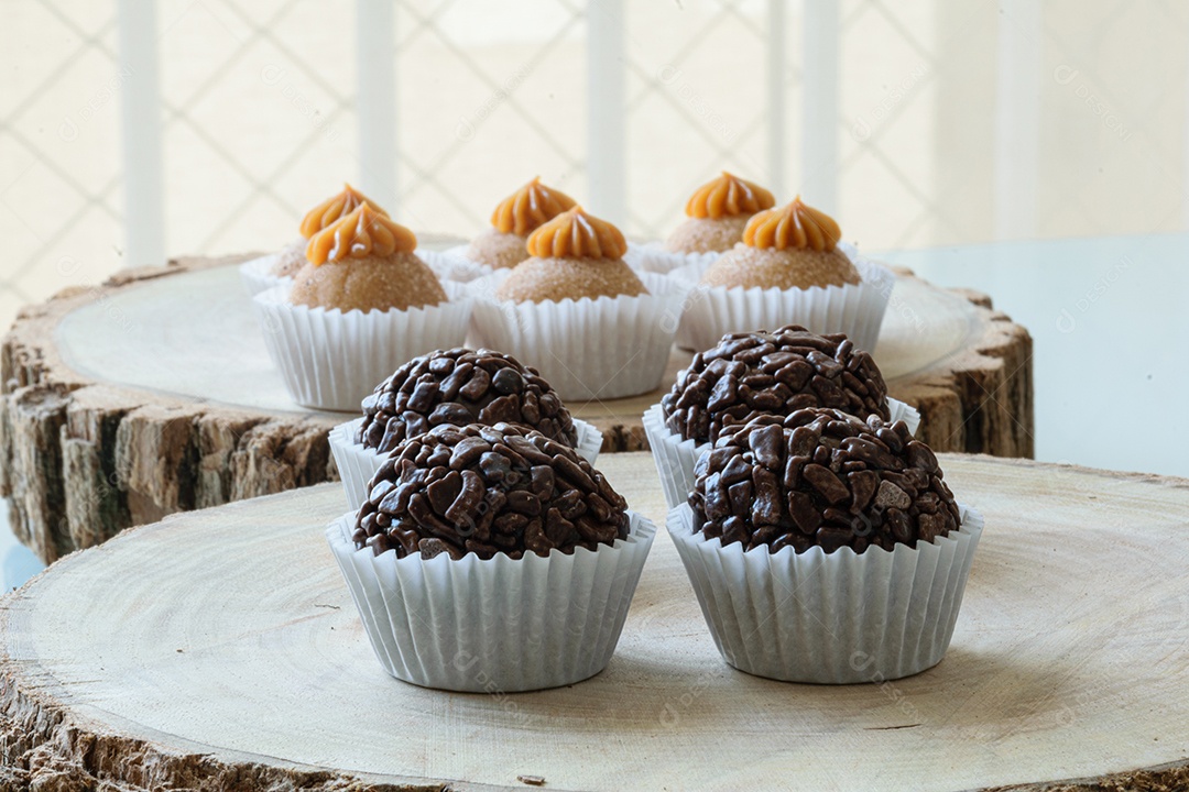 Brigadeiros de chocolate granulados alinhados em tábuas de madeira.