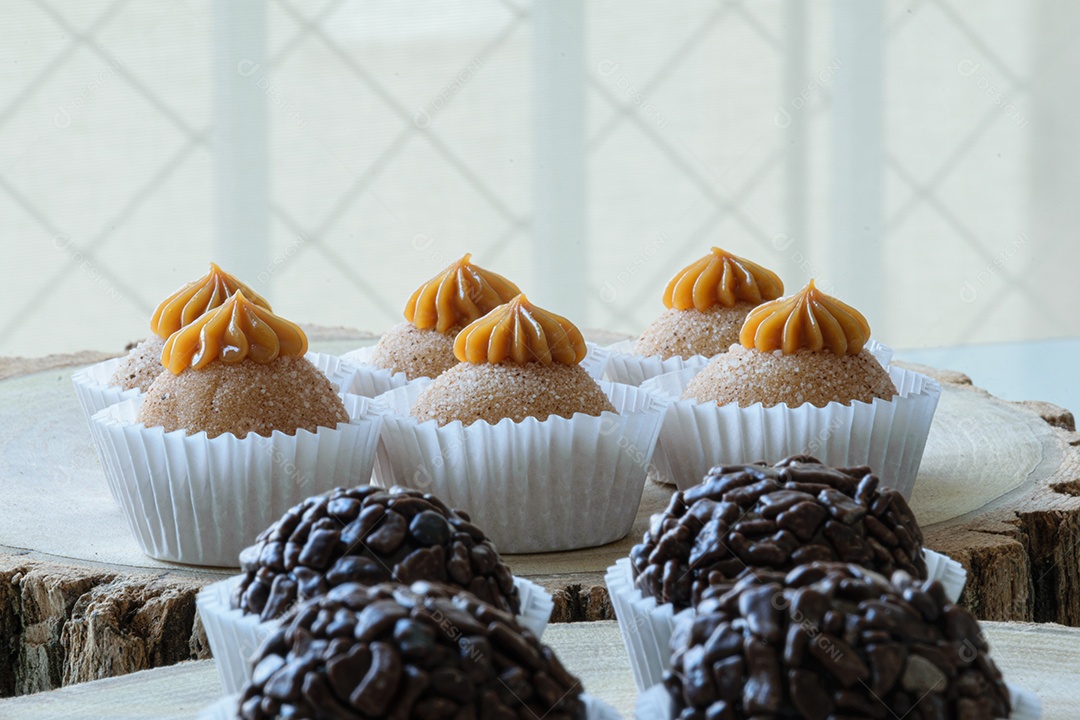 Brigadeiros de chocolate granulados alinhados em tábuas de madeira.