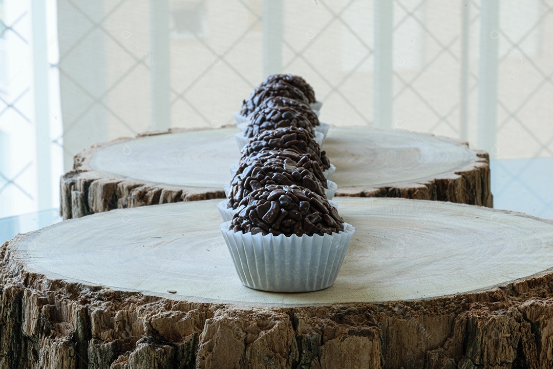 Brigadeiros de chocolate granulados alinhados em tábuas de madeira.