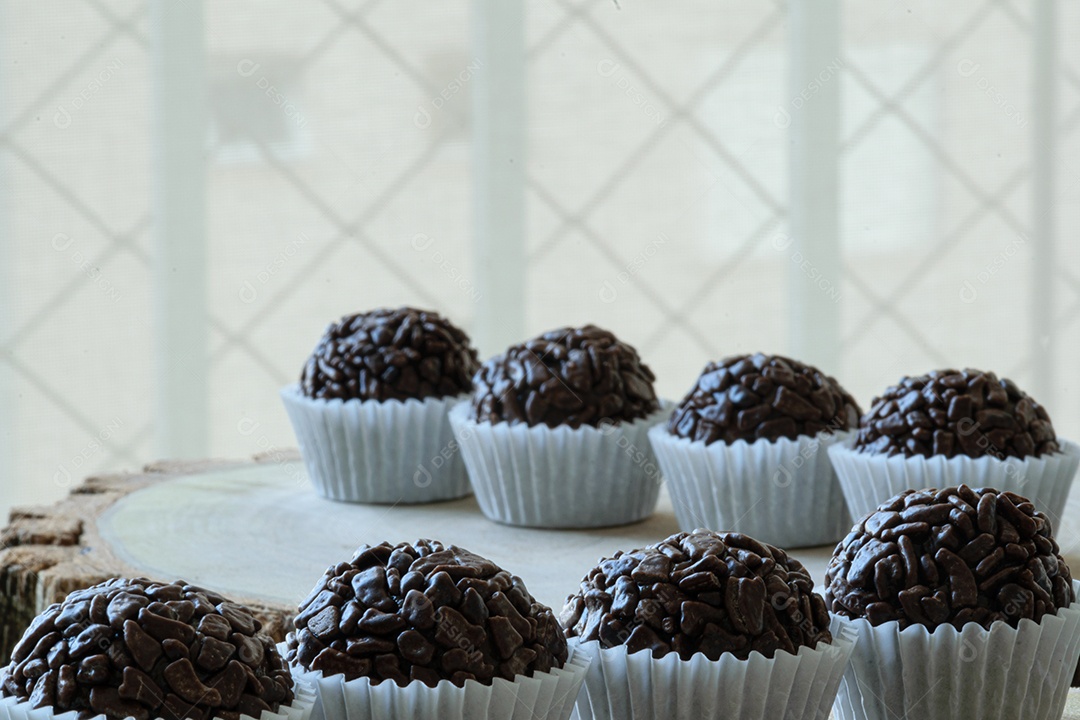 Sprinkled chocolate brigadeiros lined up on wooden boards.
