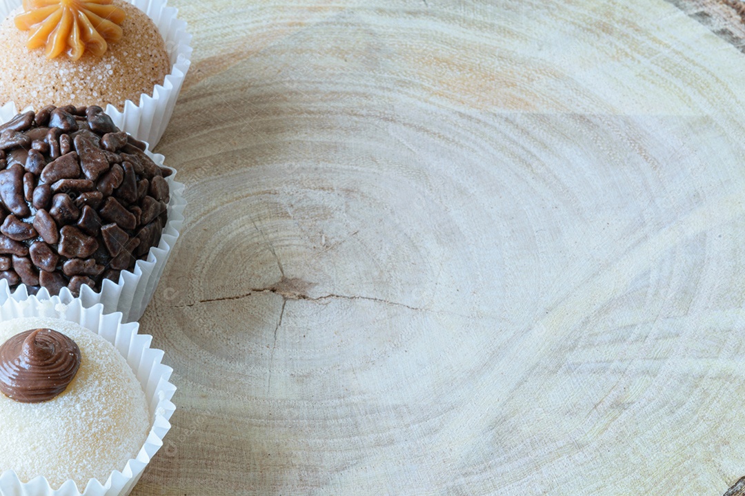 Detalhe de três brigadeiros diferentes em uma tábua de madeira