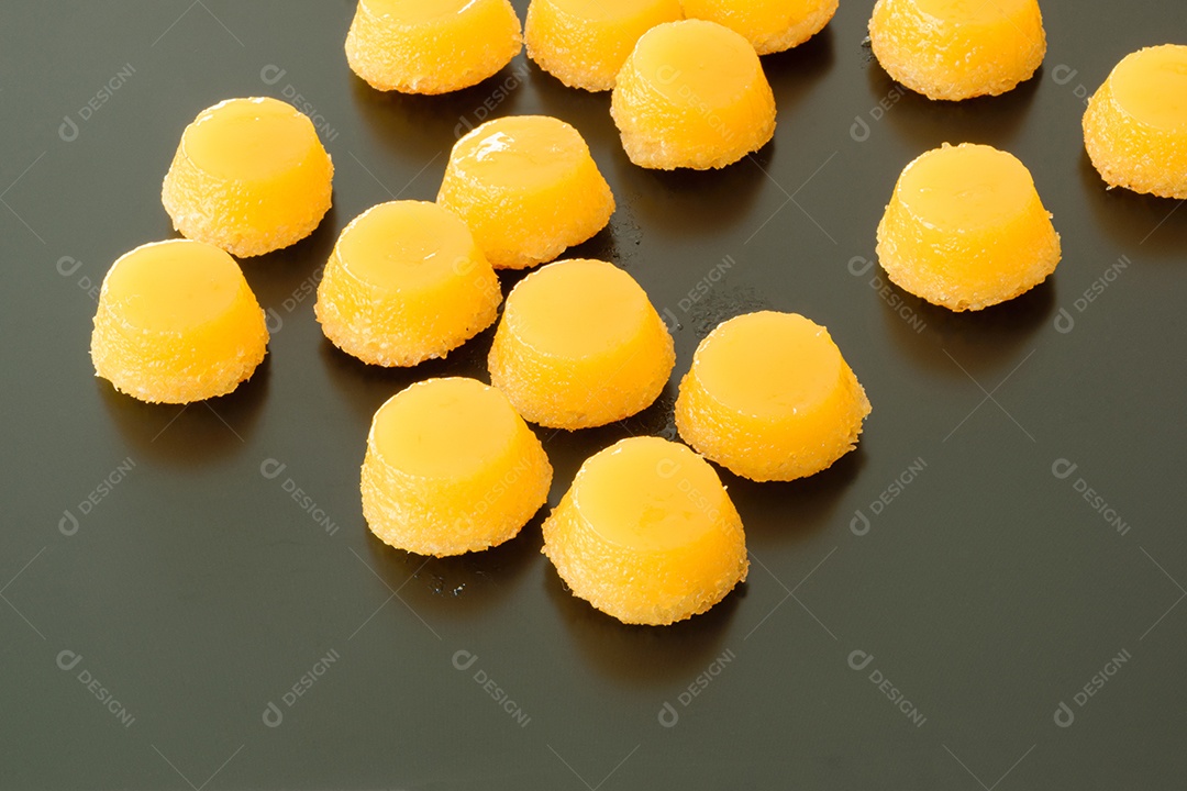 Vários quindins sobre fundo preto fosco. Doce tradicional brasileiro.