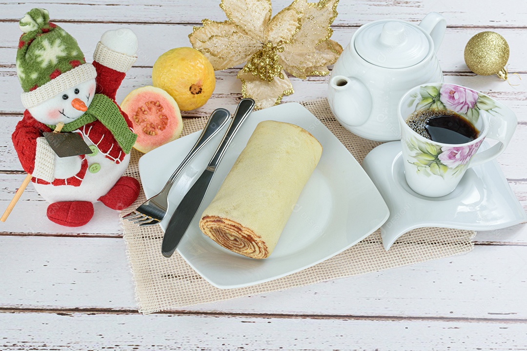 Bolo de rolo fatiado em prato vermelho ao lado de goiabas.