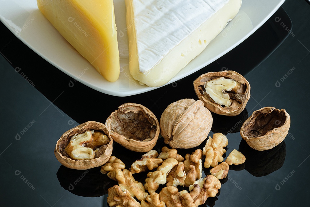 Nozes ao lado de uma taça de vinho tinto, queijo parmesão e queijo brie.
