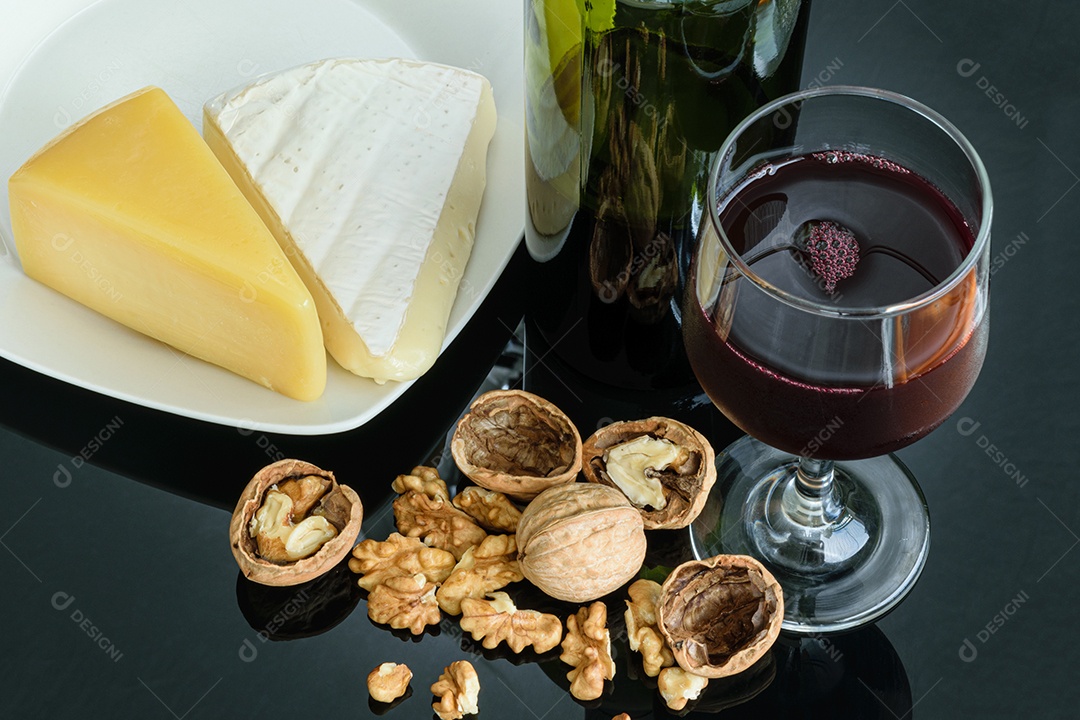 Nozes ao lado de uma taça de vinho tinto, queijo parmesão e queijo