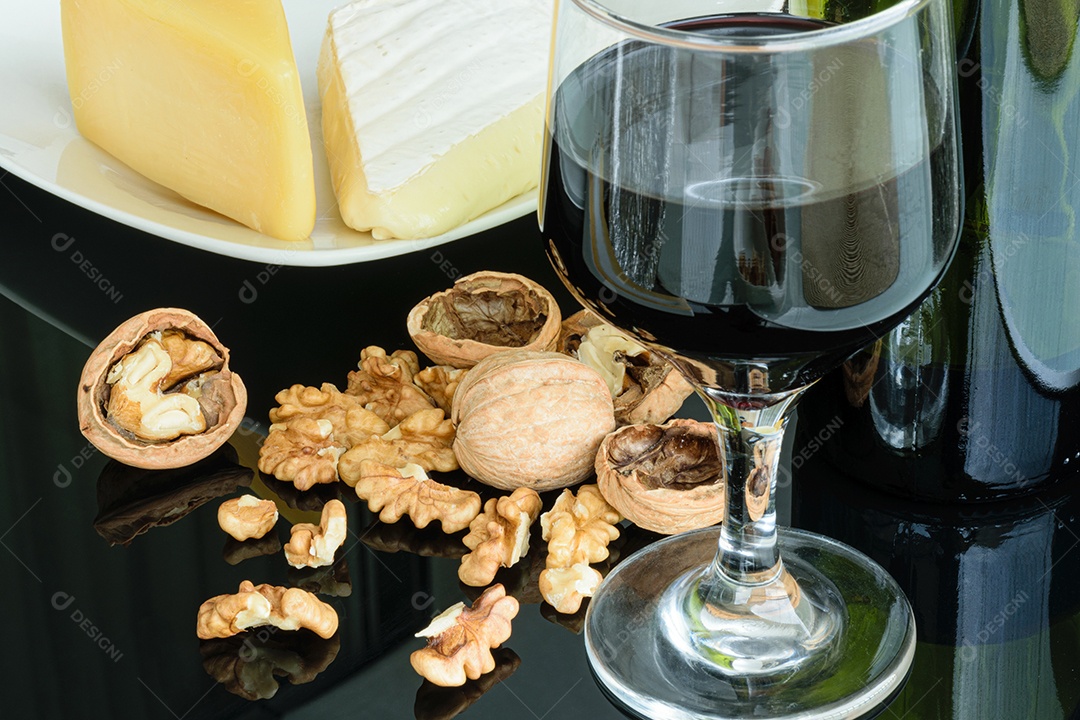 Nozes ao lado de uma taça de vinho tinto, queijo parmesão e queijo brie.