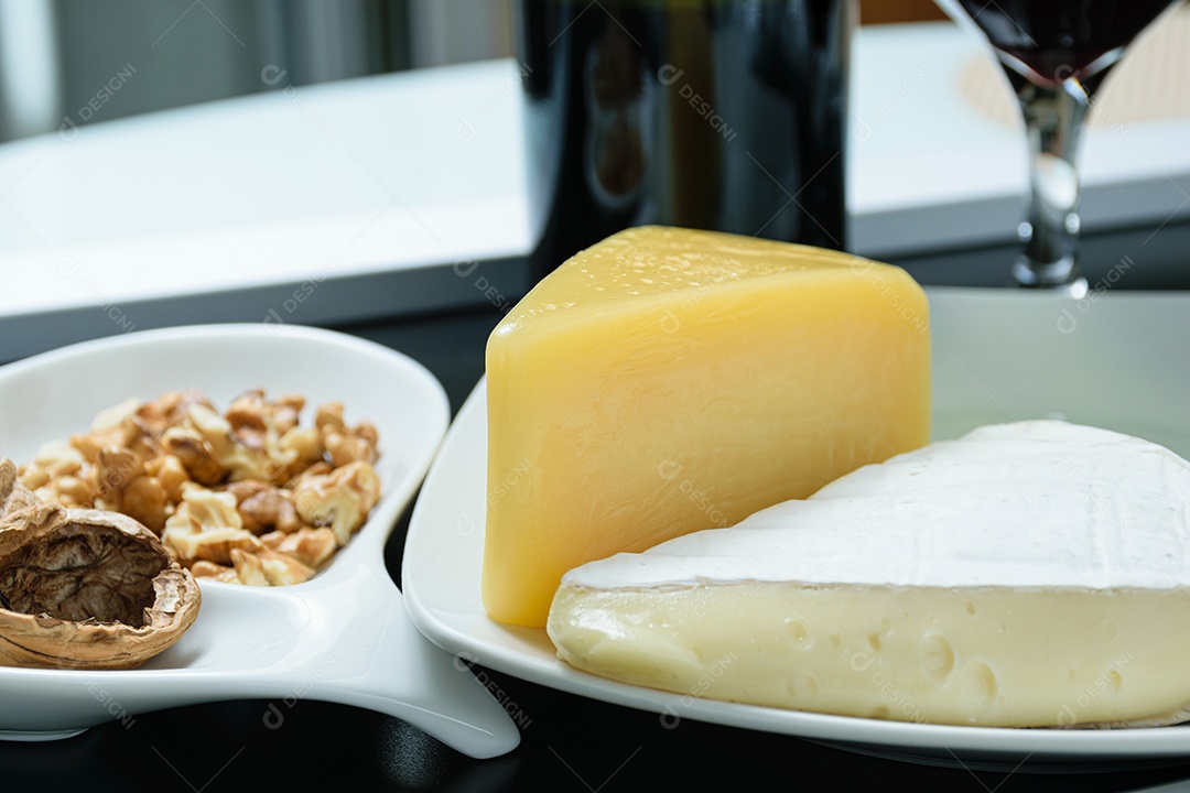 Queijos parmesão e brie ao lado de uma porção de nozes