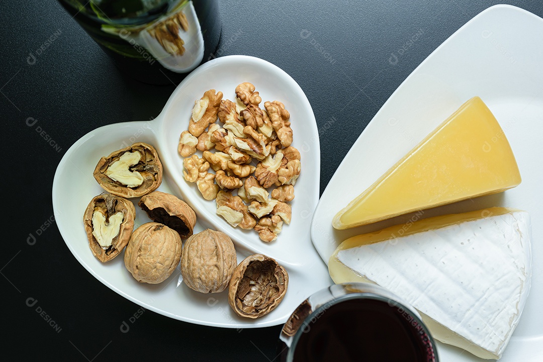 Queijos parmesão e brie ao lado de uma porção de nozes