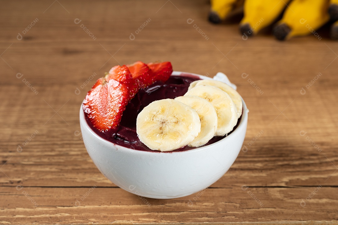 Tigela branca de açaí brasileiro congelado com paçoca, morango e banana.