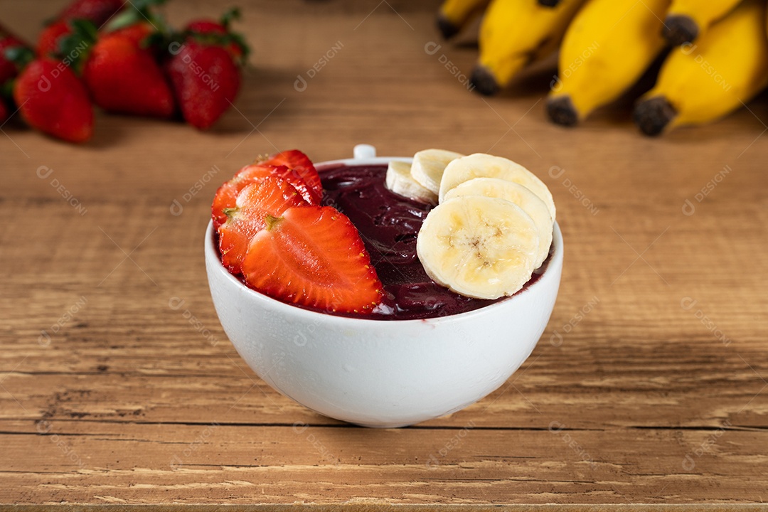 Tigela branca de açaí brasileiro congelado com paçoca, morango e banana.