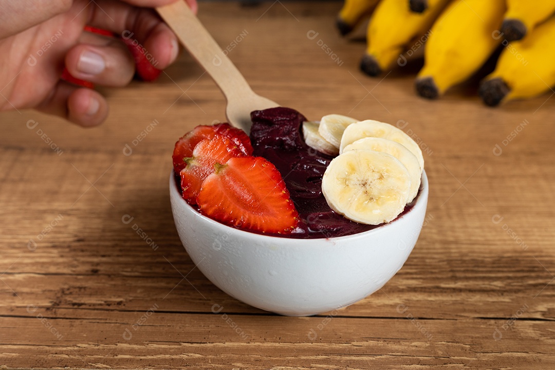 White bowl of frozen Brazilian açaí with paçoca, strawberry and banana.