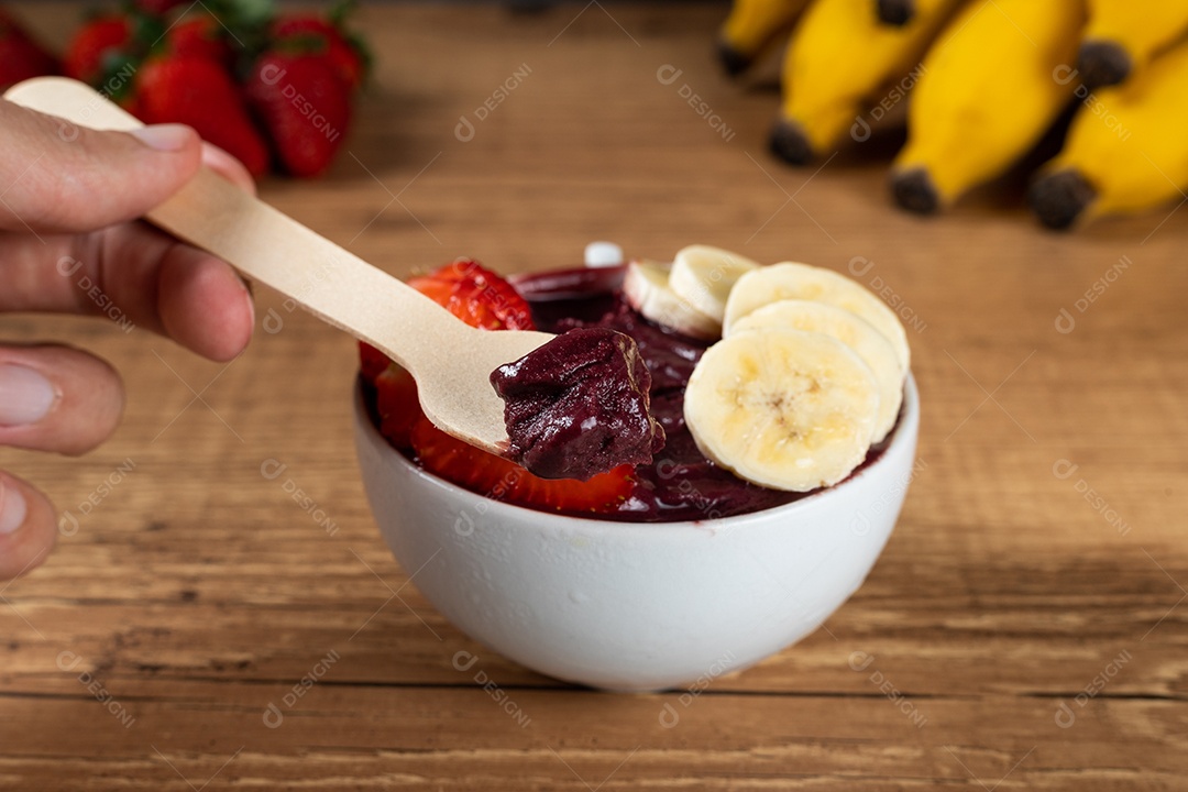 Tigela branca de açaí brasileiro congelado com paçoca, morango e banana.