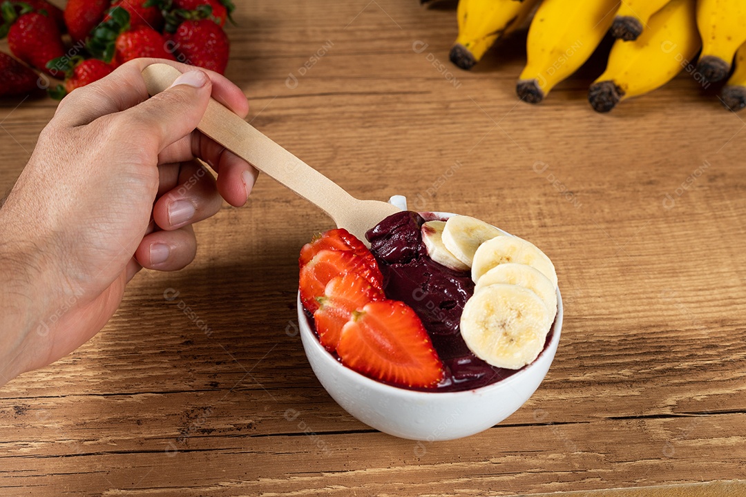 Tigela branca de açaí brasileiro congelado com paçoca, morango e banana.