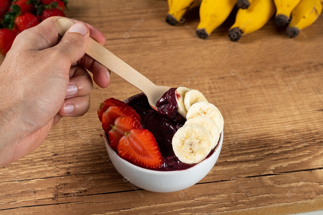 Tigela branca de açaí brasileiro congelado com paçoca, morango e banana.