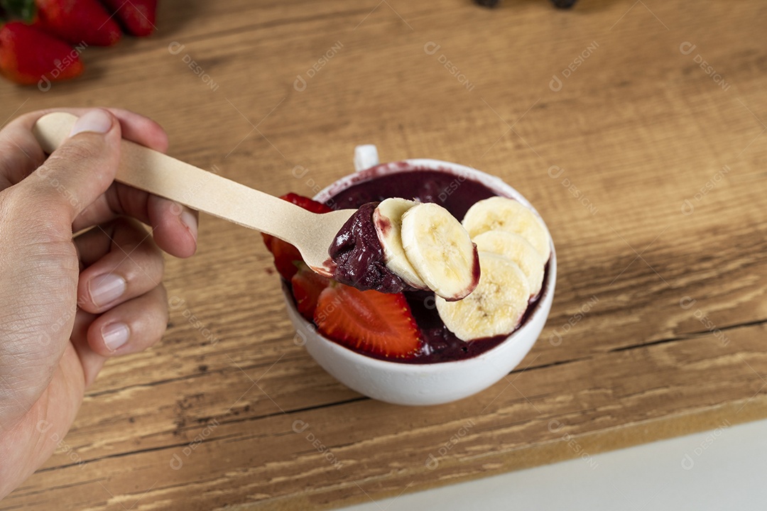 Tigela branca de açaí brasileiro congelado com paçoca, morango e banana.