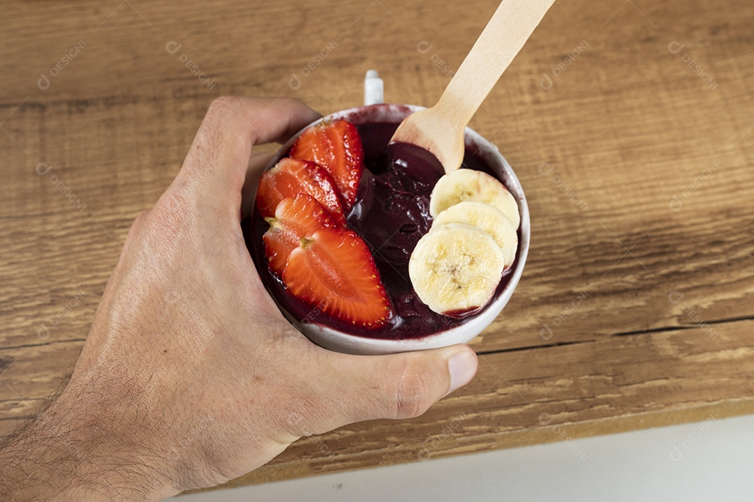 Tigela branca de açaí brasileiro congelado com paçoca, morango e banana.