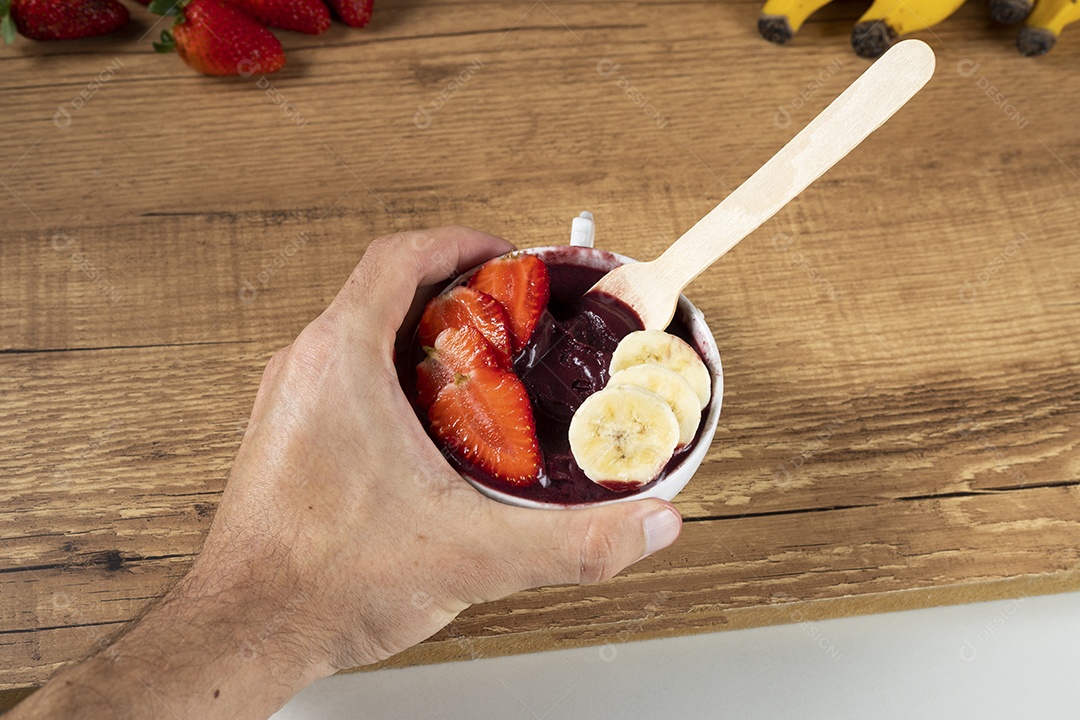 Tigela branca de açaí brasileiro congelado com paçoca, morango e banana.