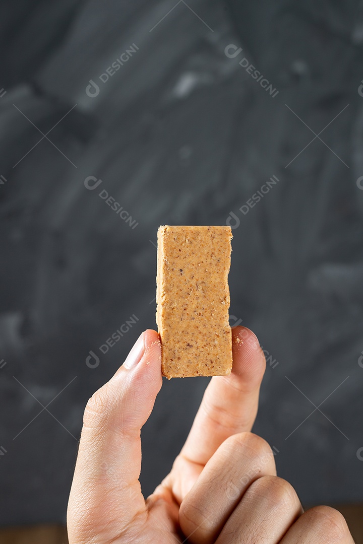 Dedos segurando um Doce de Amendoim Brasileiro chamado Paçoca.