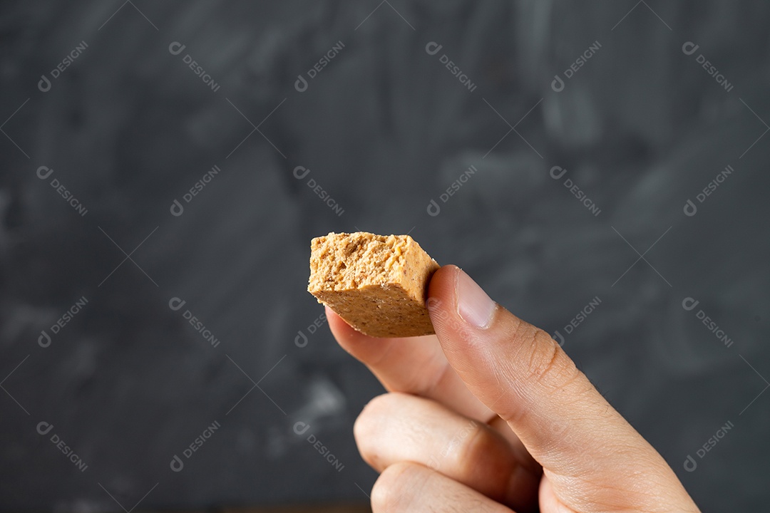 Dedos segurando um Doce de Amendoim Brasileiro chamado Paçoca.