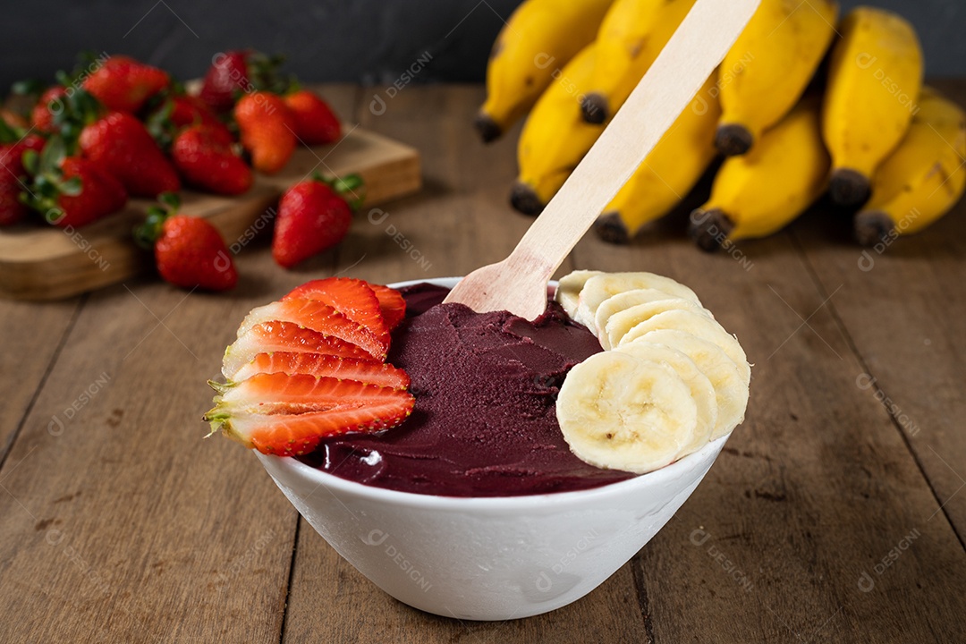 Tigela branca de açaí brasileiro congelado com paçoca, morango e banana.