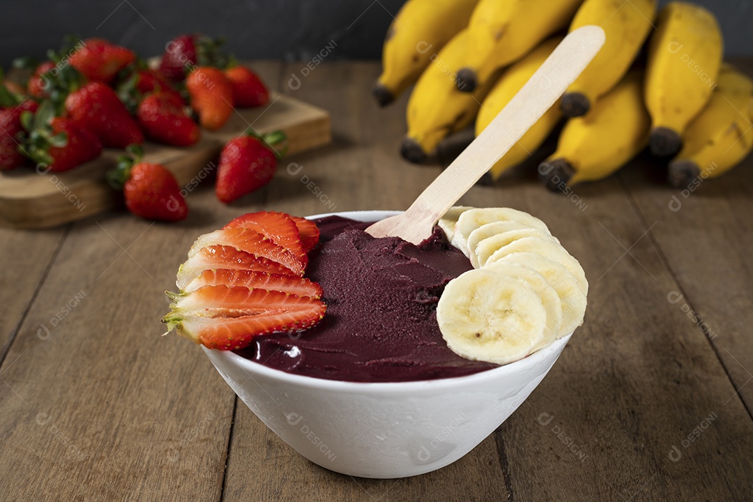 Tigela branca de açaí brasileiro congelado com paçoca, morango e banana.