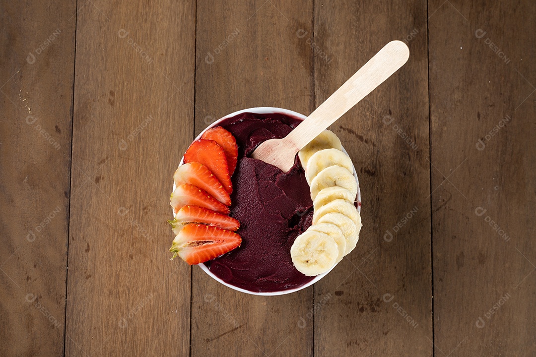 Tigela branca de açaí brasileiro congelado com paçoca, morango e banana.