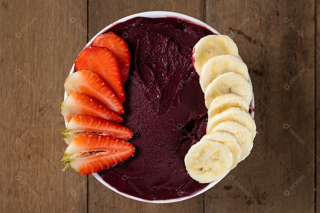 Tigela branca de açaí brasileiro congelado com paçoca, morango e banana.